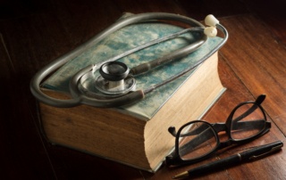 Stethoscope with eyeglasses,pen and antique book.