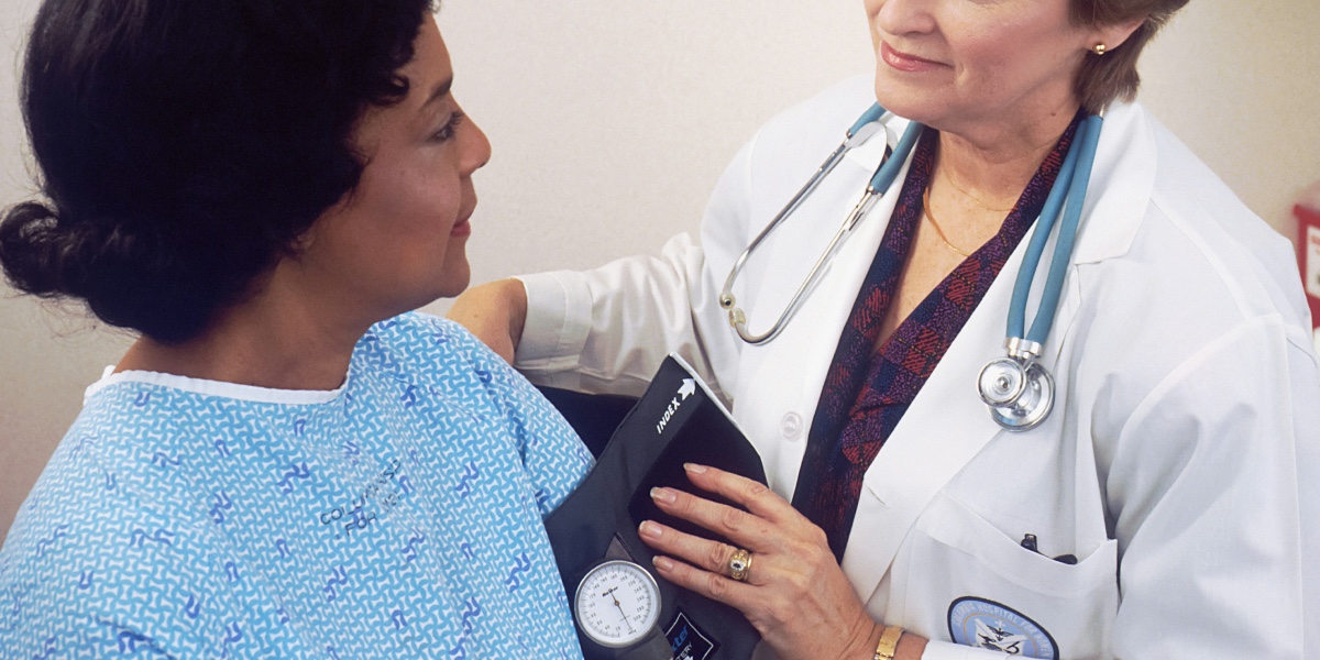 A doctor uses a blood-pressure monitor on a patient.