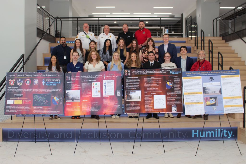 People stand lined up on a set of stairs, holding and displaying a series of handmade posters.