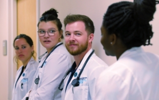 Doctors in white coats standing in hospital hallway.