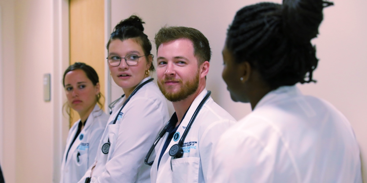 Doctors in white coats standing in hospital hallway.