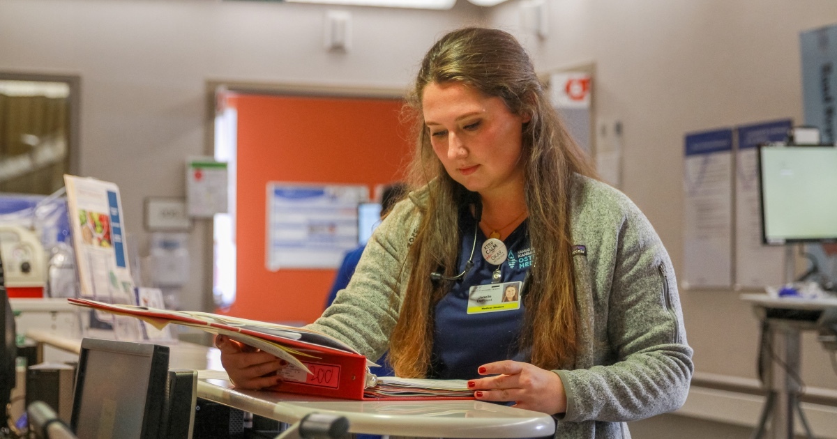 A student doctor reviewing a chart in a clinical setting.