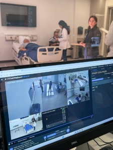 Simulated clinical scenario with trained actors serving as patients, recreating real care situations. Scenarios are recorded and monitored through the LearningSpace platform, visible on screen.