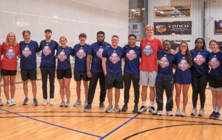 KansasCOM studnets pose with Gradey Dickcamp on a basketball court.